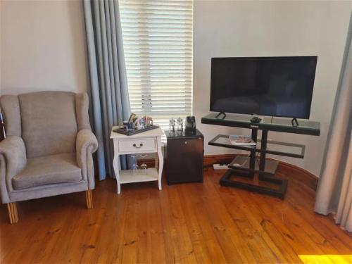 a living room with a chair and a flat screen tv at Castle On The Heads in Knysna