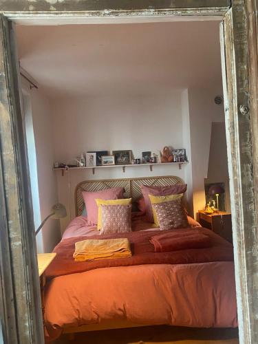 - une chambre dotée d'un grand lit avec des draps et des oreillers orange dans l'établissement Your Favorite Nest In Paris, à Paris