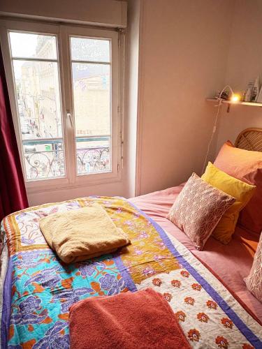 une chambre avec un lit avec des oreillers et une fenêtre dans l'établissement Your Favorite Nest In Paris, à Paris