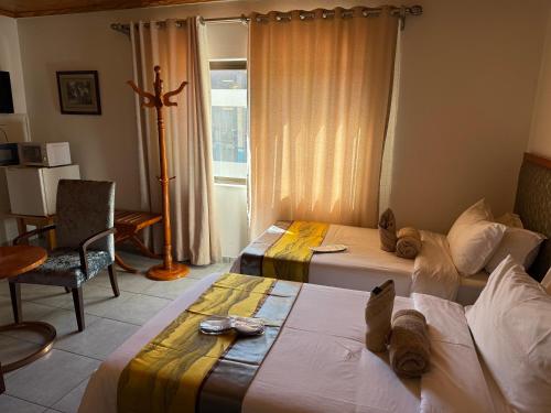 a hotel room with two beds and a window at Hotel Pension Steiner in Windhoek