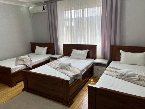 una habitación con tres camas y una ventana en MASSAGET HOTEL, en Nukus