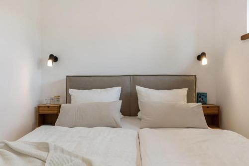 une chambre avec deux lits avec draps blancs et oreillers dans l'établissement Luxus-Ferienwohnung DS11, à Fehmarn