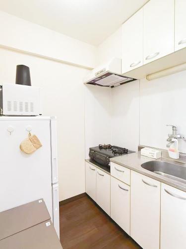 a white kitchen with a stove and a sink at 高輪ー703 in Tokyo
