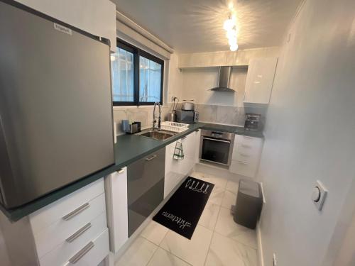 une cuisine avec des armoires blanches et un comptoir noir dans l'établissement Rankos, à Malakoff