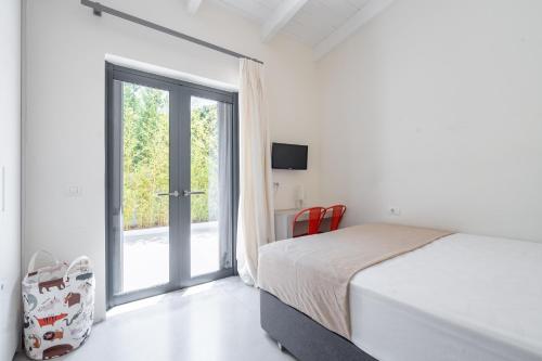 Un dormitorio blanco con una cama y una ventana. en Maya Luxury Residence, en Aegenitissa