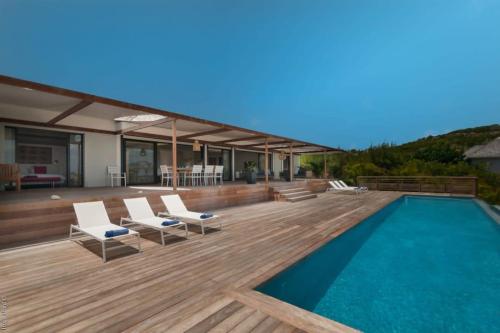 Petit Cul de SacにあるHilltop Deluxe Villa in Petit Cul De Sacのスイミングプールとウッドデッキ付きの家