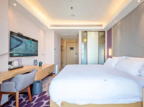 a hotel room with a bed and a desk and a tv at Lavande Hotel Shenzhen International Convention and Exhibition Center Fuhai West Subway Station in Shenzhen