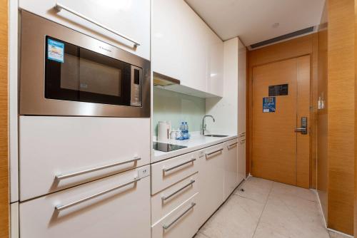 a kitchen with white cabinets and a microwave at Bulgari Serviced Residences Guangzhou in Guangzhou