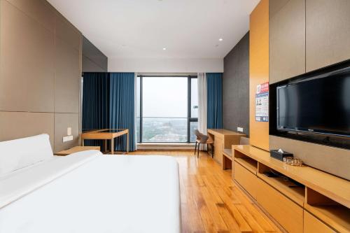 a hotel room with a bed and a flat screen tv at Bulgari Serviced Residences Guangzhou in Guangzhou