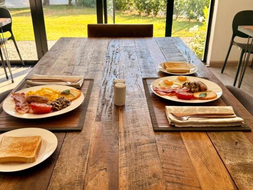 a wooden table with plates of breakfast food on it at NO4 Lilliput - Sandton Executive Guest House - OPENING SPECIAL in Sandton