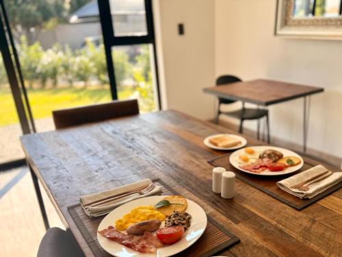 two plates of breakfast food on a wooden table at NO4 Lilliput - Sandton Executive Guest House - OPENING SPECIAL in Sandton