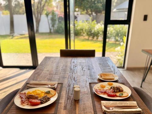 a wooden table with two plates of breakfast food on it at NO4 Lilliput - Sandton Executive Guest House - OPENING SPECIAL in Sandton