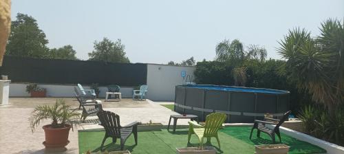 a group of chairs sitting on a lawn with a swimming pool at Villa Zaira in Baia Verde