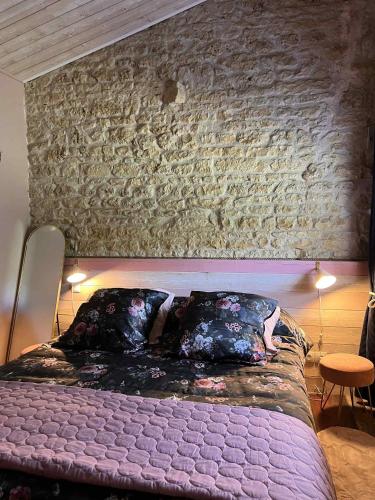 Ce lit se trouve dans une chambre dotée d'un mur en briques. dans l'établissement Gîte de charme romantique avec Spa privatif l'Echappée bulles, à Chambon
