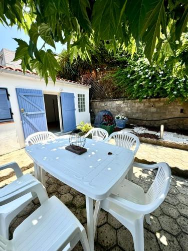 une table blanche et des chaises assises sur une terrasse dans l'établissement Maison avec jardin et proche mer, à Propriano