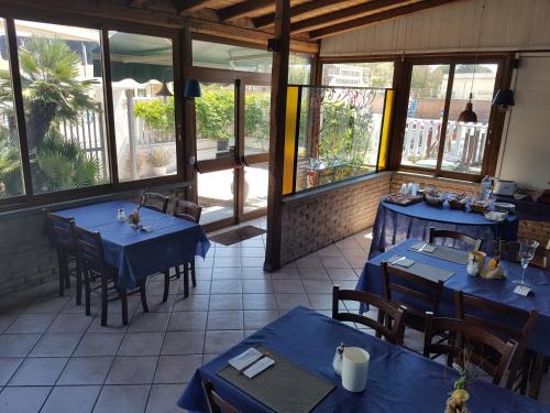 een restaurant met blauwe tafels en stoelen en ramen bij Albergo Villa Marina in Anzio