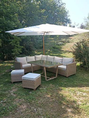 a table and chairs under an umbrella in the grass at Villa Strada dei Monti Sibillini in Montefortino