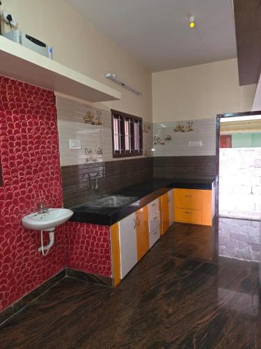 a bathroom with a sink and a red wall at Royal Peters Holiday Homes, Main Falls, Coutralam in Kuttālam