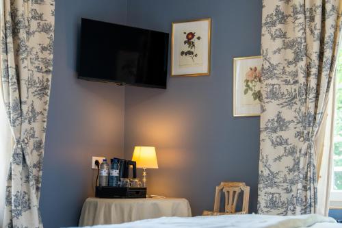 a bedroom with a bed and a tv on the wall at Villa Saint-Lager - Séjour de charme au cœur du Beaujolais in Saint-Lager