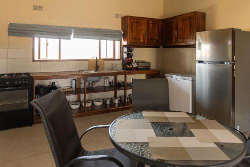 a kitchen with a table and a stainless steel refrigerator at Rain Tree Camp in Chunga