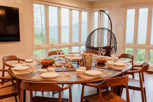 a dining room with a table and chairs and windows at Villa atami in Atami