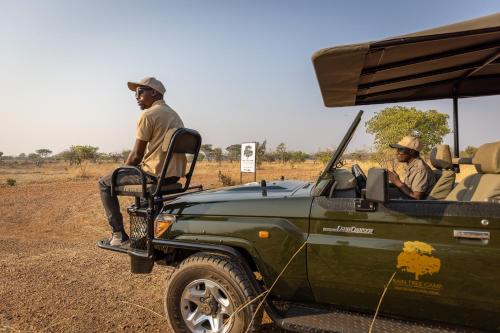 two men sitting in the back of a green jeep at Rain Tree Camp in Chunga