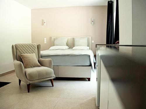 a bedroom with a bed and a chair and a chair at Hôtel-Restaurant Belle'man in Longevelle-sur-Doubs