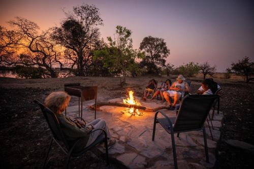 a group of people sitting around a fire at Rain Tree Camp in Chunga