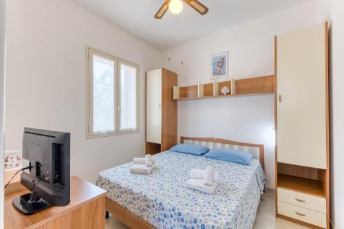 a bedroom with a bed and a flat screen tv at Villa Terra Rossa in Torre San Giovanni Ugento
