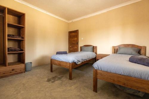a bedroom with two beds and a book shelf at Rain Tree Camp in Chunga