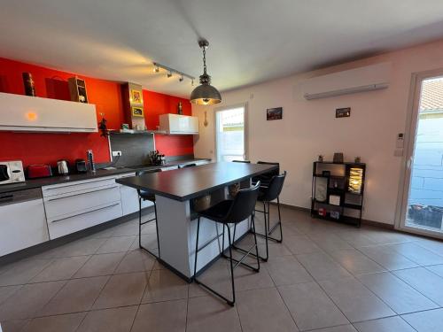 a kitchen with red walls and a island with stools at Le Yéti T4 air-conditioned Lyon Eurexpo stadium LDLC arena in Chassieu