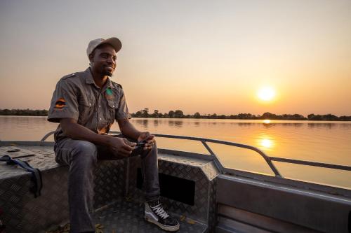 a man sitting on the back of a boat on the water at Rain Tree Camp in Chunga