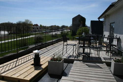 a wooden deck with chairs and tables and a fence at Visby Innerstad Lägenheter & Rum in Visby