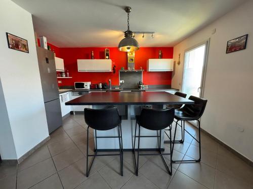 a kitchen with red walls and a table and chairs at Le Yéti T4 air-conditioned Lyon Eurexpo stadium LDLC arena in Chassieu
