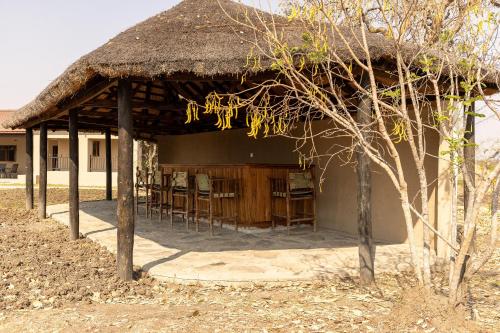 a pavilion with chairs and a straw roof at Rain Tree Camp in Chunga