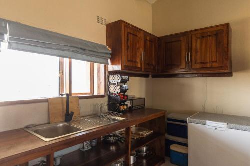 a kitchen with wooden cabinets and a sink and a window at Rain Tree Camp in Chunga