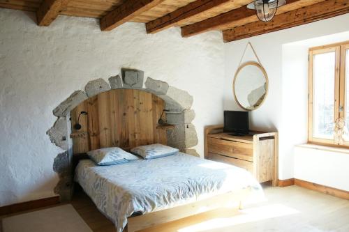 - une chambre avec un lit doté d'une tête de lit en bois et d'un miroir dans l'établissement Chaleureuse maison de village, à Marignier
