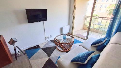 salon z kanapą i telewizorem w obiekcie L'ILOT avec balcon, mignon et charmant, un havre de paix au cœur du centre-ville w Cannes