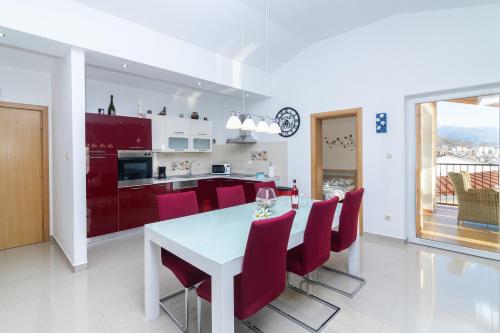 a kitchen and dining room with a white table and red chairs at Seabreeze Apartments with Shared Jacuzzi in Senj
