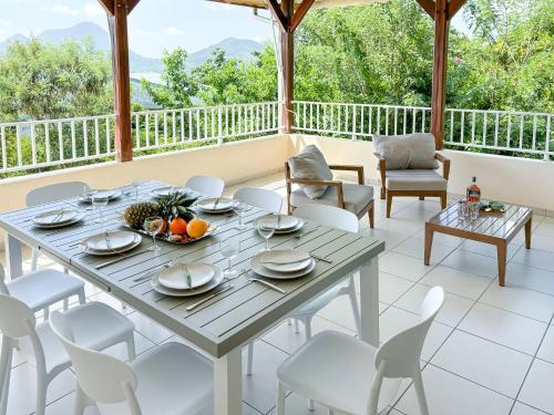 une salle à manger avec une table et des chaises sur un porche dans l'établissement Labote, duplex vue mer, Diamant, au Diamant