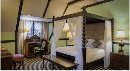 a bedroom with a four poster bed and a desk at The Lakehouse Cameron Highlands in Ringlet