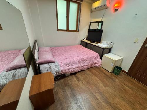 um pequeno quarto com duas camas e uma televisão em Samsung Hotel em Gangneung