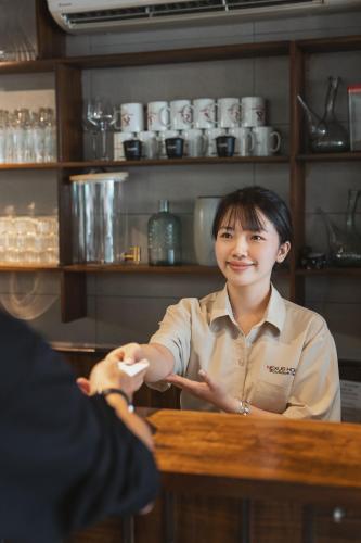 a woman sitting at a table talking to a customer at Nexus House Nguyen Binh Khiem - Near Saigon Zoo & Botanical Gardens in Ho Chi Minh City