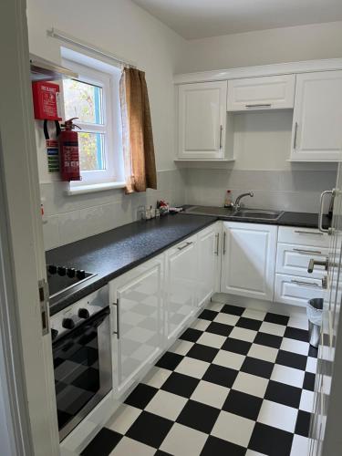 a kitchen with white cabinets and a black and white checkered floor at Casey's Of Baltimore Collection in Baltimore