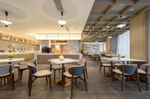 a restaurant with tables and chairs and a kitchen at Atour Hotel Jiangnan Moore Zhongshan Road Jiaxing in Jiaxing