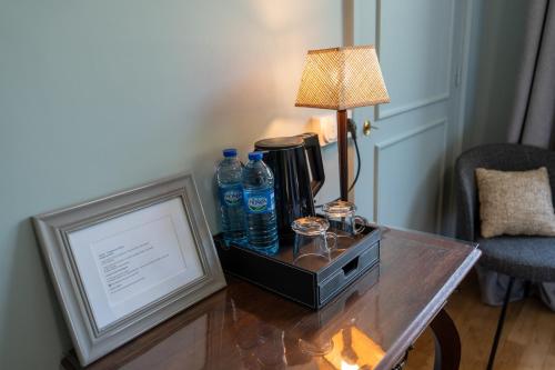 a table with a lamp and water bottles on it at Villa Saint-Lager - Séjour de charme au cœur du Beaujolais in Saint-Lager
