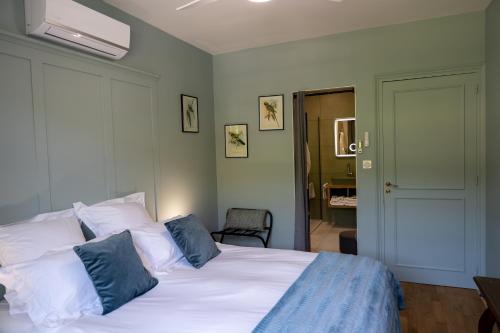a bedroom with a bed with white sheets and blue pillows at Villa Saint-Lager - Séjour de charme au cœur du Beaujolais in Saint-Lager