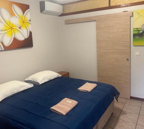a bedroom with a blue bed with two towels on it at Le Fautaua in La Foa