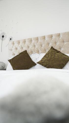 a white bed with two pillows and a white headboard at Lux Apartment in Gatwick in Crawley