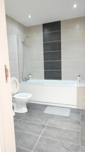 a bathroom with a toilet and a tub and a sink at Lux Apartment in Gatwick in Crawley